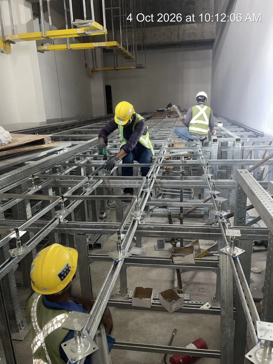 Installers fastening raised floor stringers and pedestals onto a steel understructure