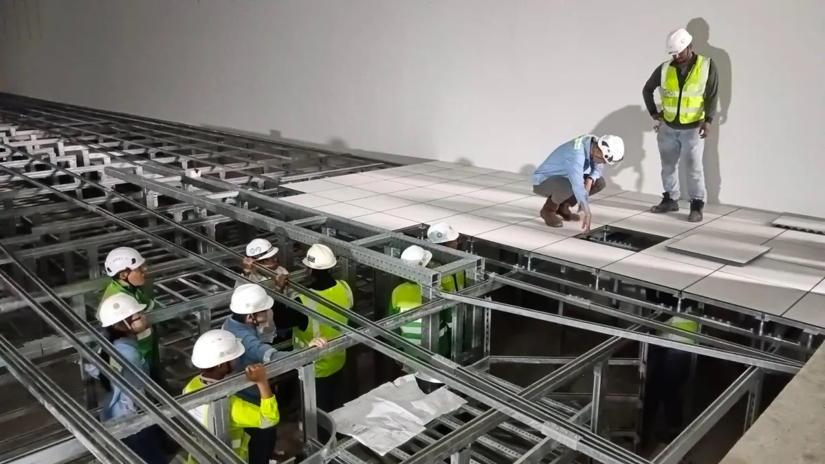 Momentum installers fitting raised floor panels over a deep steel understructure at IWMF